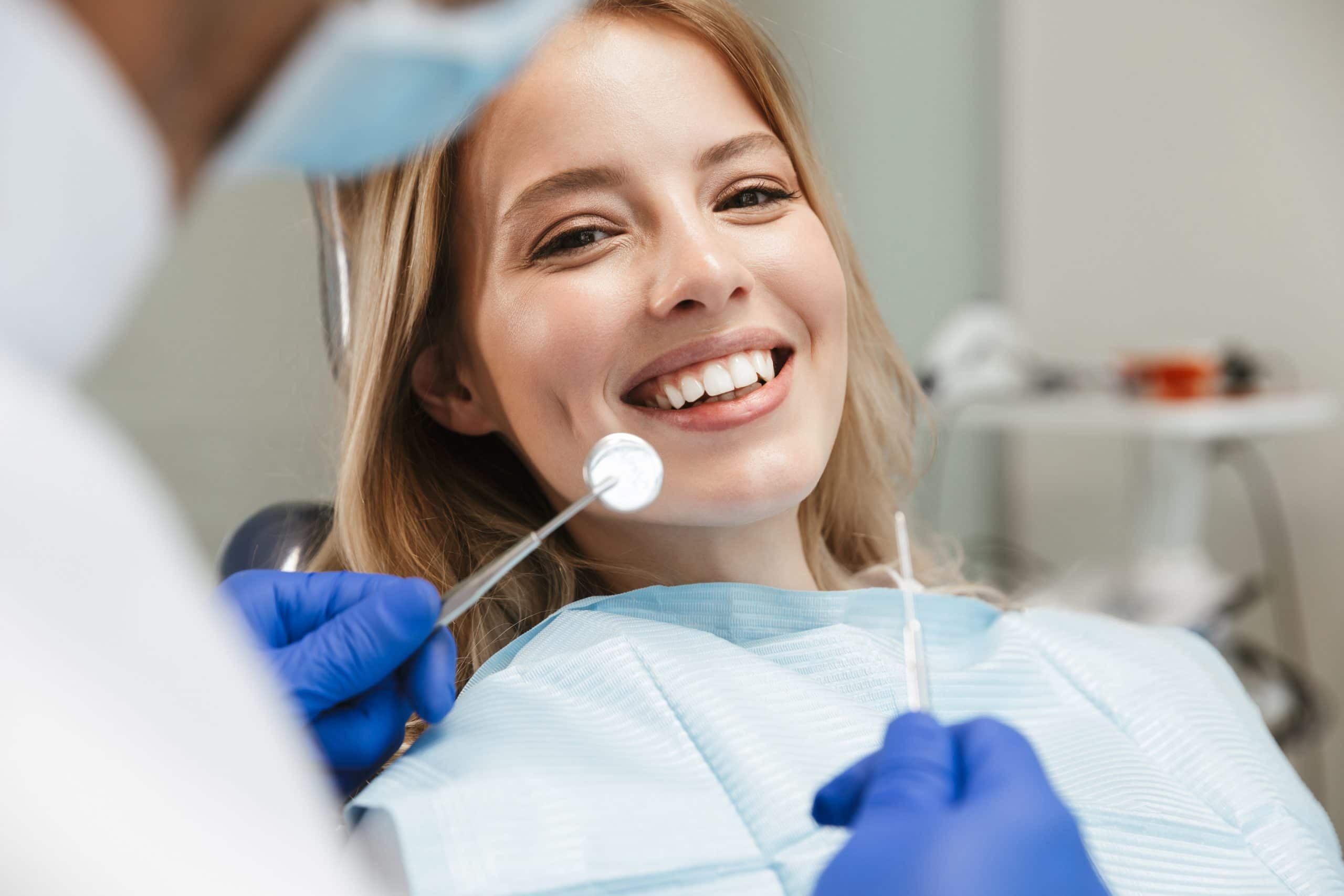 Image of satisfied woman sitting in dental chair while professional